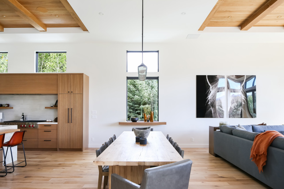 Cette image montre une salle à manger design avec un mur blanc, un sol en bois brun, un sol marron, poutres apparentes et un plafond en bois.
