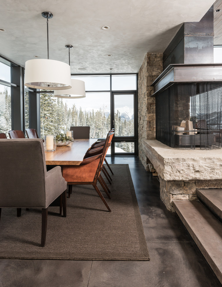 Design ideas for an expansive contemporary dining room in Other with beige walls, concrete flooring, a two-sided fireplace and a stone fireplace surround.