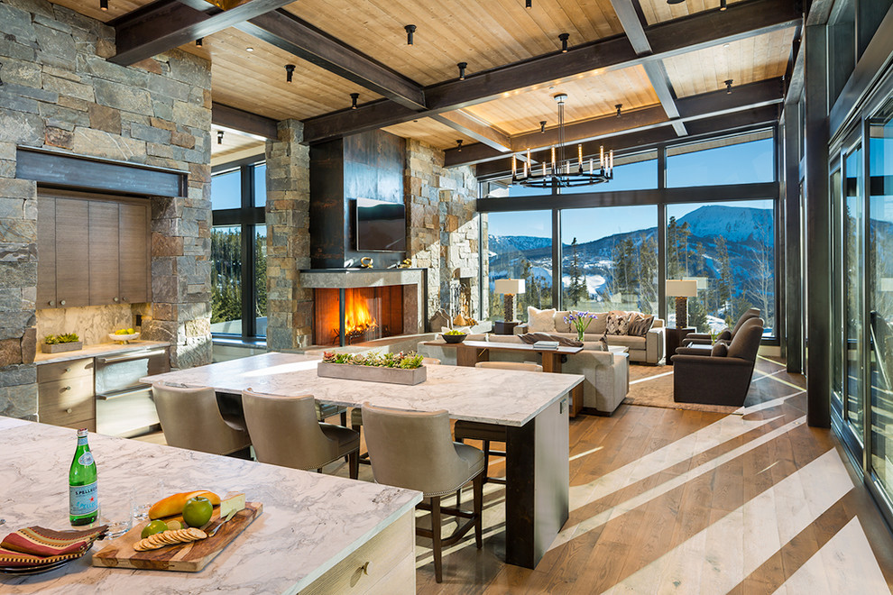 Example of a large mountain style medium tone wood floor and brown floor great room design in Other with a stone fireplace and a corner fireplace