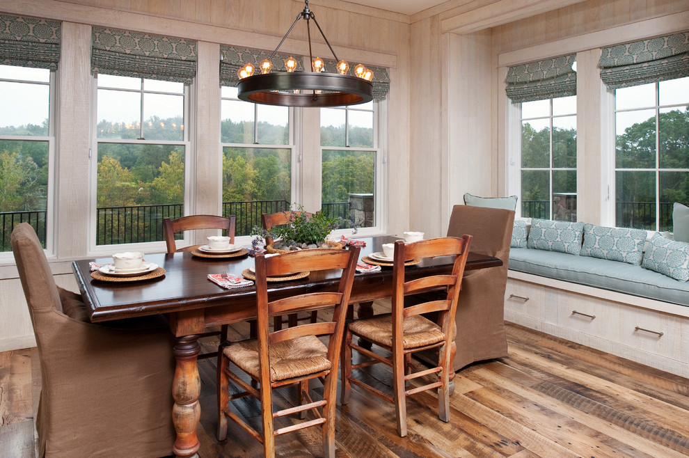 Cette image montre une salle à manger chalet de taille moyenne avec un sol en bois brun, un mur blanc et aucune cheminée.