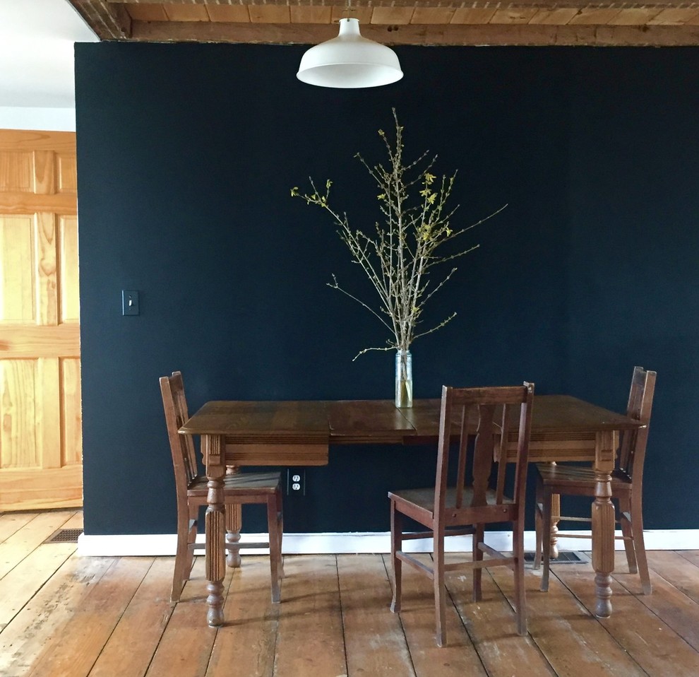 Immagine di una sala da pranzo aperta verso la cucina country di medie dimensioni con pareti nere, pavimento in legno massello medio e pavimento marrone