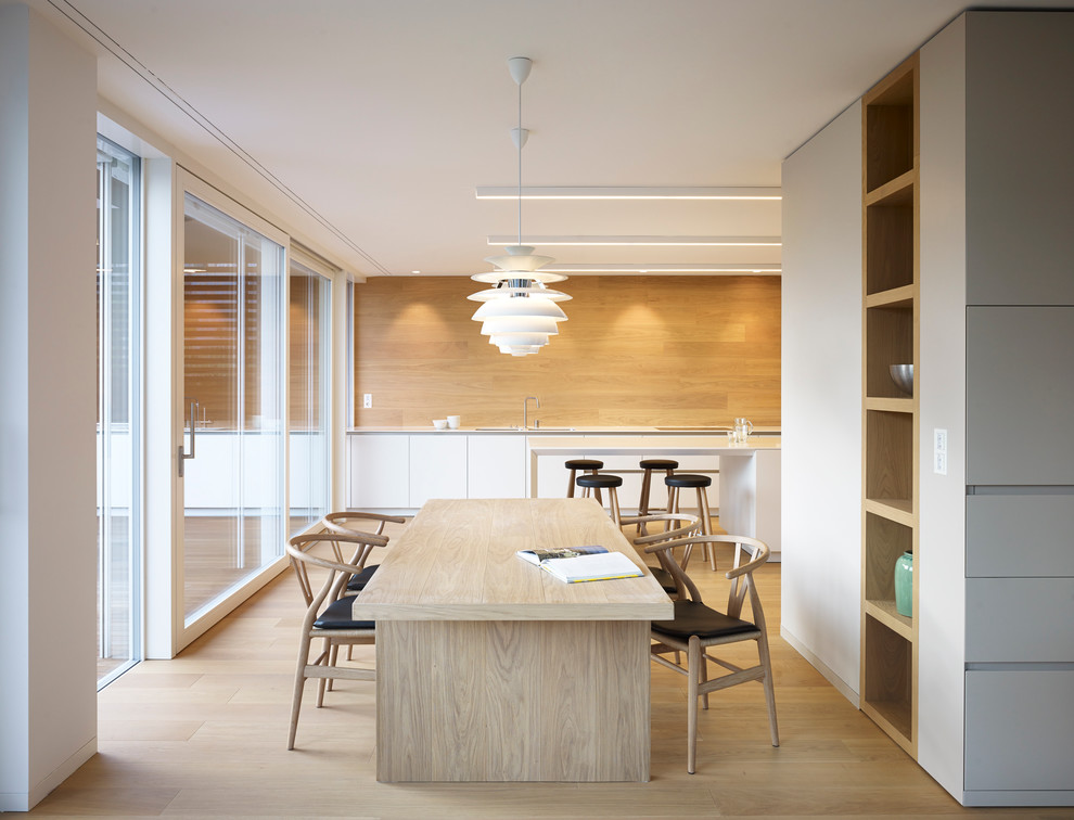 Пример оригинального дизайна: кухня-столовая в скандинавском стиле с белыми стенами и светлым паркетным полом