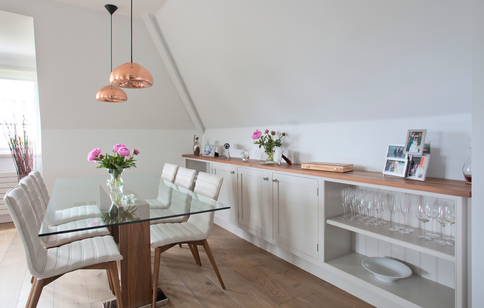 Immagine di una sala da pranzo aperta verso la cucina tradizionale con pareti bianche e pavimento in legno massello medio