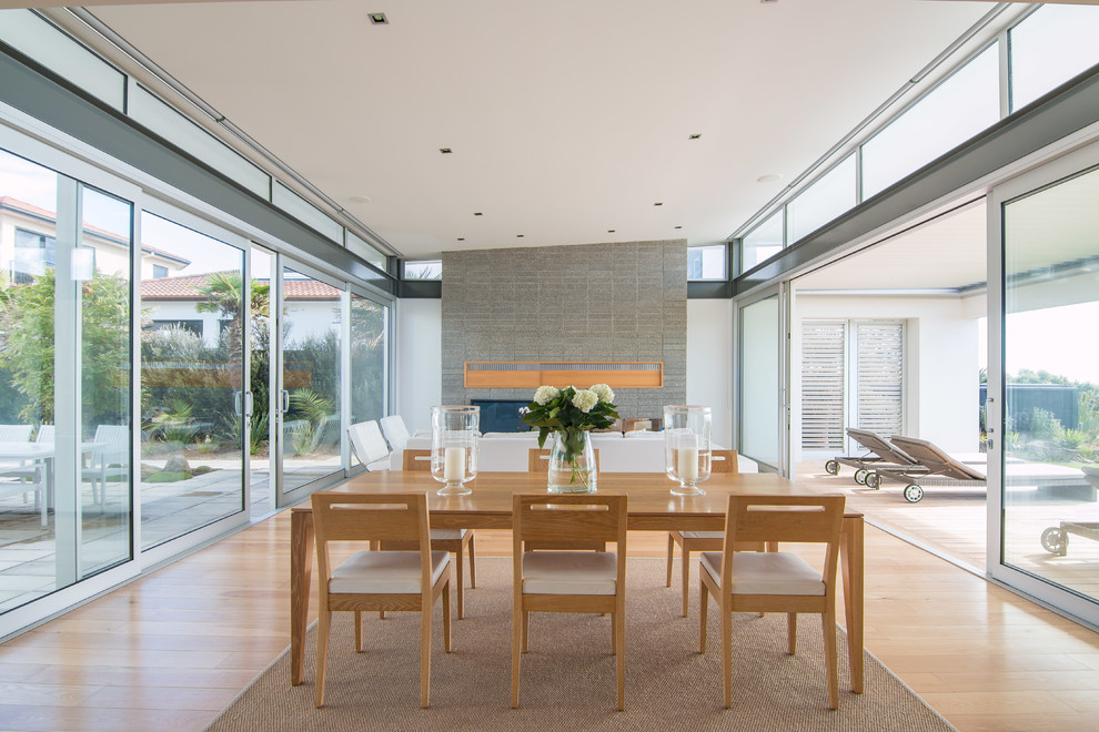 Источник вдохновения для домашнего уюта: большая кухня-столовая в стиле модернизм с белыми стенами, паркетным полом среднего тона, стандартным камином и фасадом камина из бетона