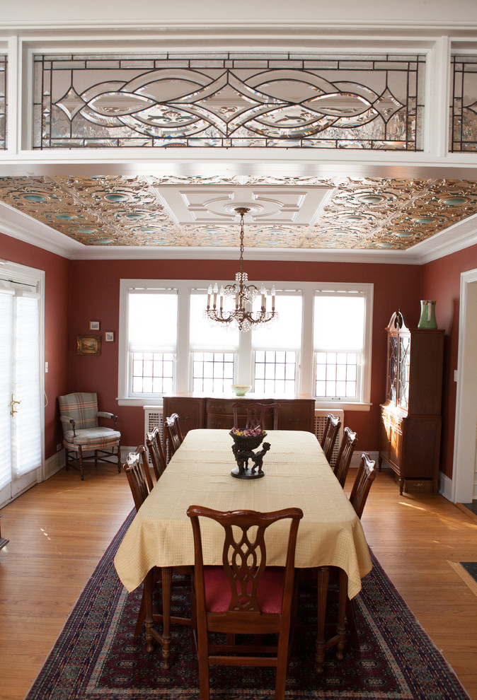 Aménagement d'une petite salle à manger ouverte sur le salon classique avec un mur rouge et parquet clair.
