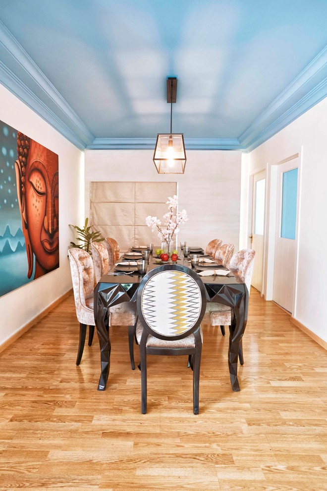 Example of a mid-sized trendy medium tone wood floor and brown floor dining room design in Mumbai with white walls