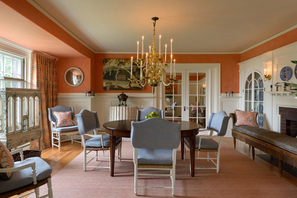 This is an example of a large traditional kitchen/dining room in Boston with orange walls, light hardwood flooring, a standard fireplace and a brick fireplace surround.