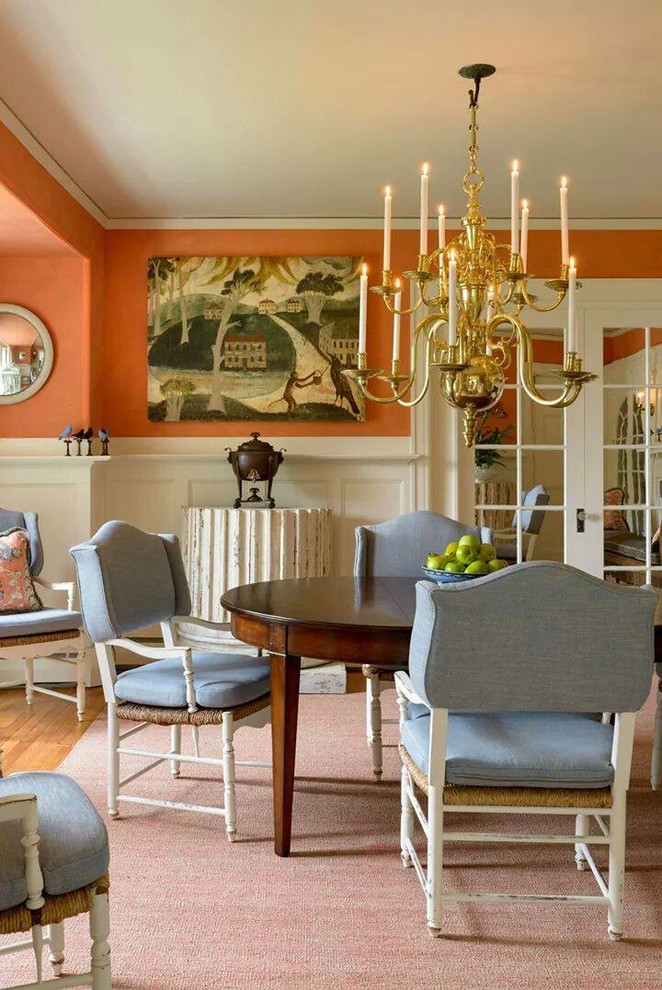 Cette photo montre une salle à manger chic fermée avec un mur orange et un sol en bois brun.