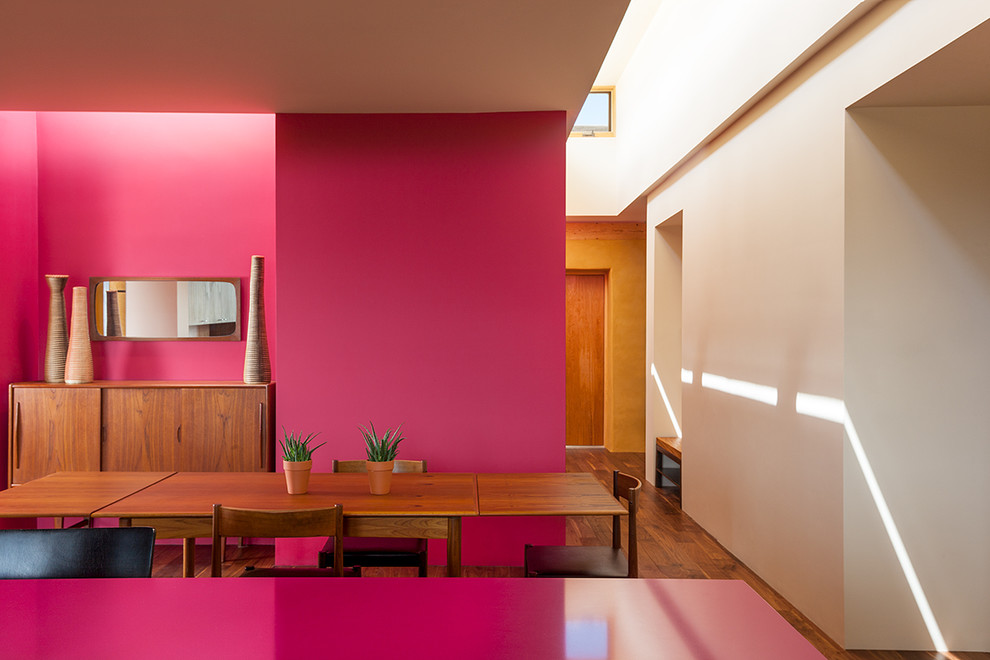 Idées déco pour une salle à manger ouverte sur la cuisine contemporaine de taille moyenne avec un mur rouge, un sol en bois brun et un sol marron.