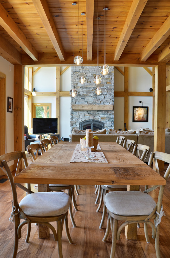 Réalisation d'une salle à manger chalet avec parquet clair et un manteau de cheminée en pierre.
