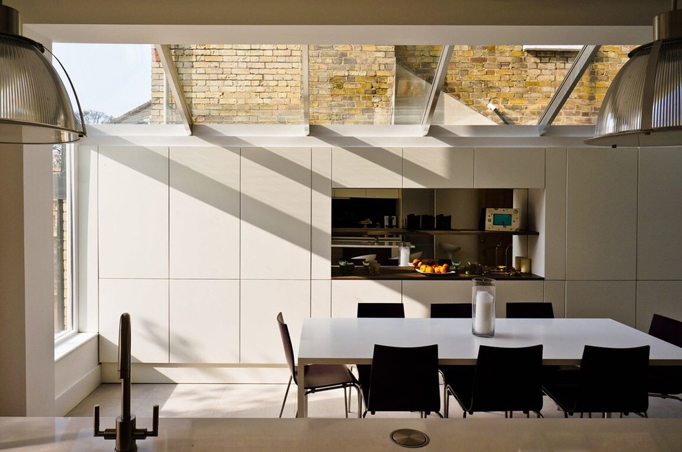 Foto på ett mellanstort funkis kök med matplats, med vita väggar och vitt golv