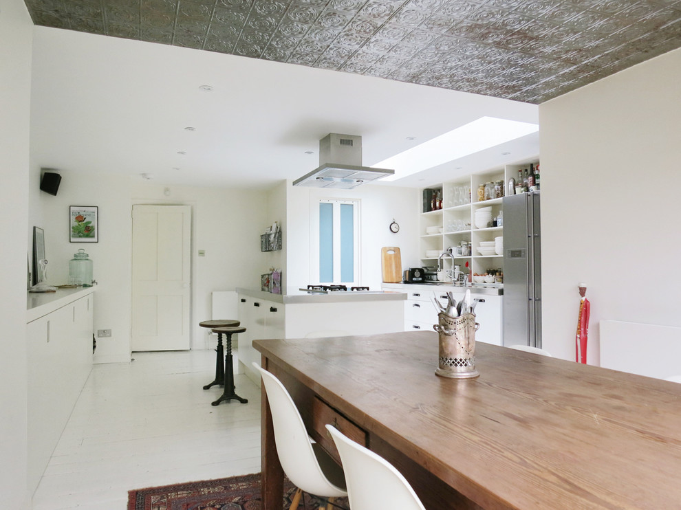 Ispirazione per una sala da pranzo aperta verso la cucina boho chic con pareti bianche, pavimento in legno verniciato e pavimento bianco