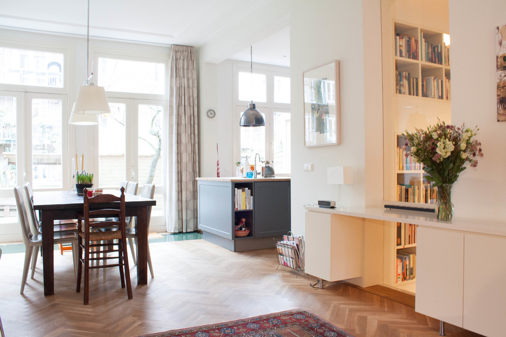 Large eclectic kitchen/dining room in Amsterdam with white walls and medium hardwood flooring.