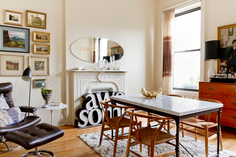 Stilmix Esszimmer mit beiger Wandfarbe, braunem Holzboden und Kamin in New York