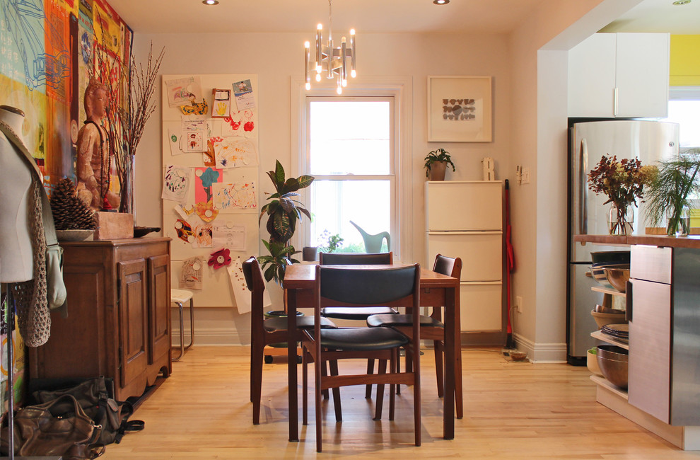 Réalisation d'une salle à manger ouverte sur la cuisine bohème avec un mur blanc et un sol en bois brun.