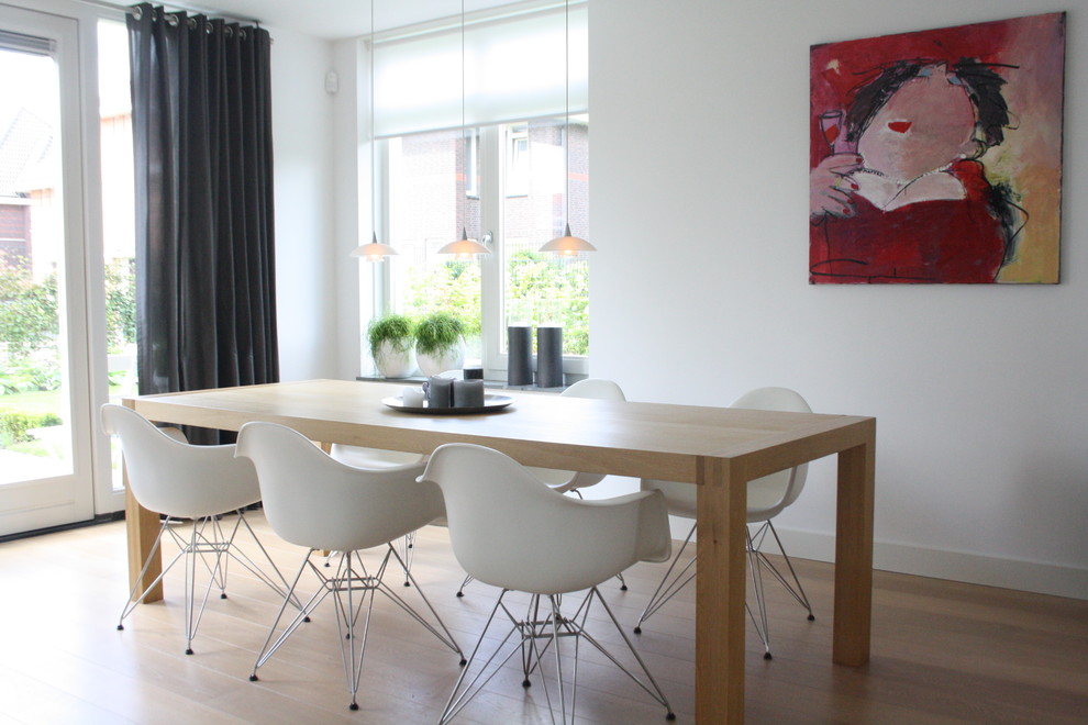 Diseño de comedor contemporáneo con paredes blancas, suelo de madera en tonos medios y cortinas