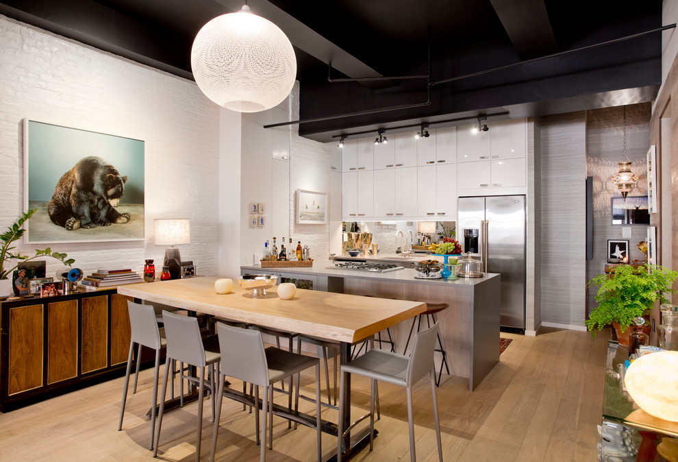 Cette photo montre une salle à manger ouverte sur la cuisine tendance avec un mur blanc, parquet clair et éclairage.