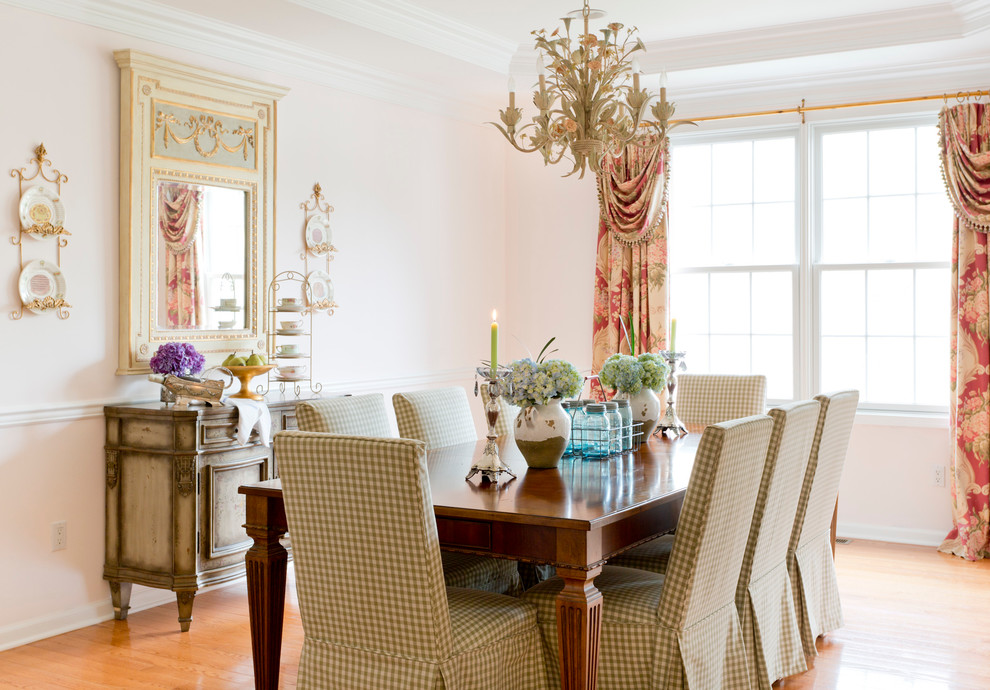 This is an example of a traditional enclosed dining room in New York with pink walls and medium hardwood flooring.