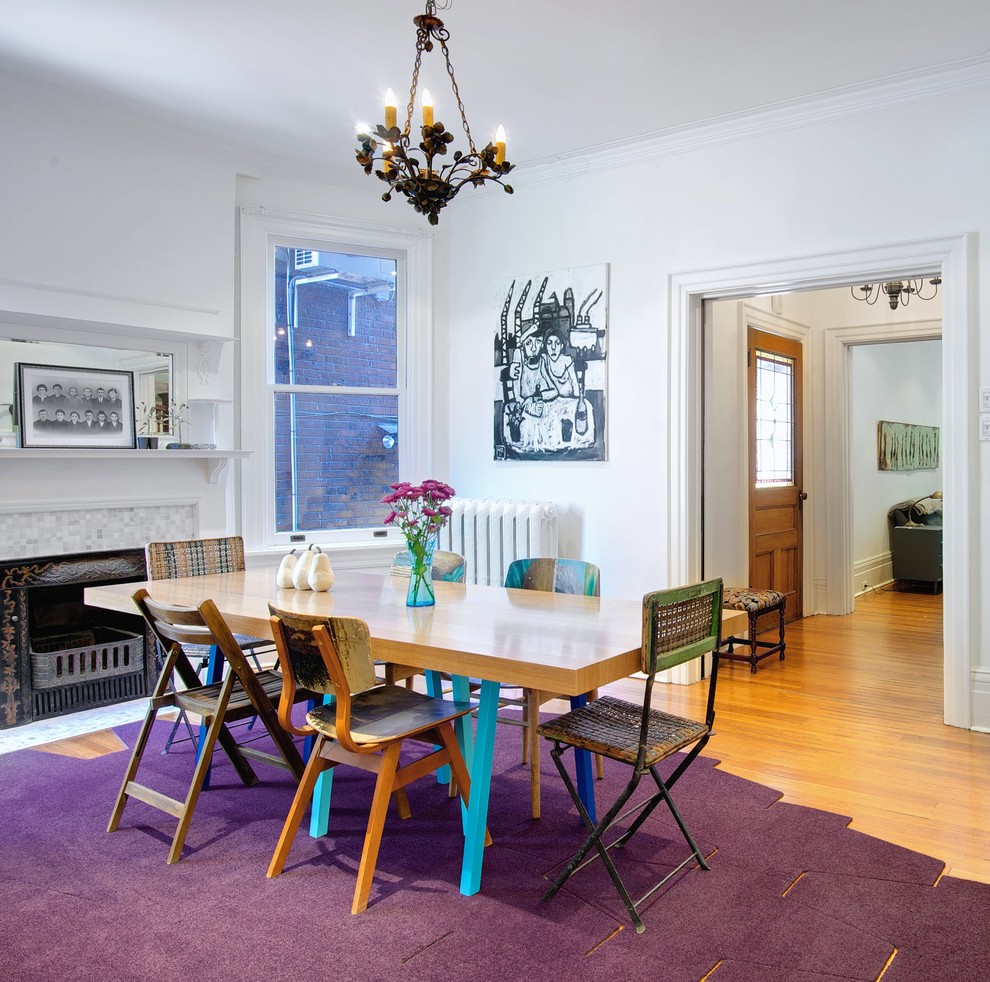 Inspiration pour une grande salle à manger bohème fermée avec un mur blanc, un sol en bois brun, une cheminée standard et un manteau de cheminée en carrelage.