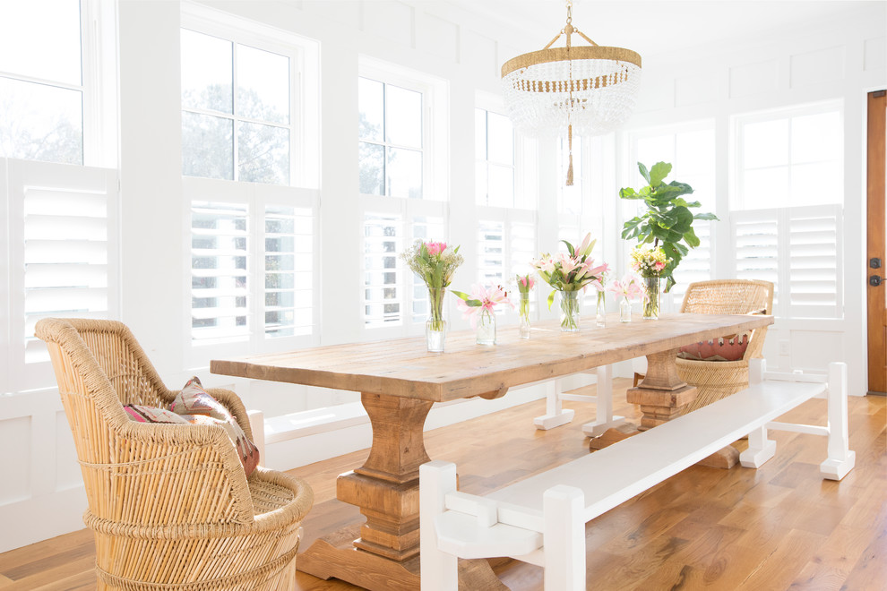 Imagen de comedor costero con paredes blancas, suelo de madera en tonos medios y suelo marrón