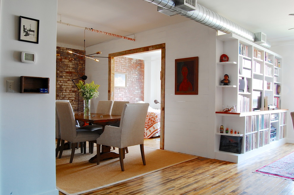 Immagine di una sala da pranzo industriale con pareti bianche e pavimento in legno massello medio
