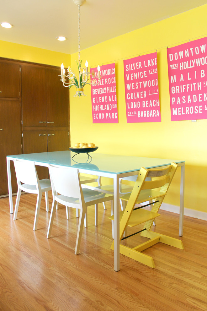 Cette image montre une salle à manger bohème avec un mur jaune et un sol en bois brun.