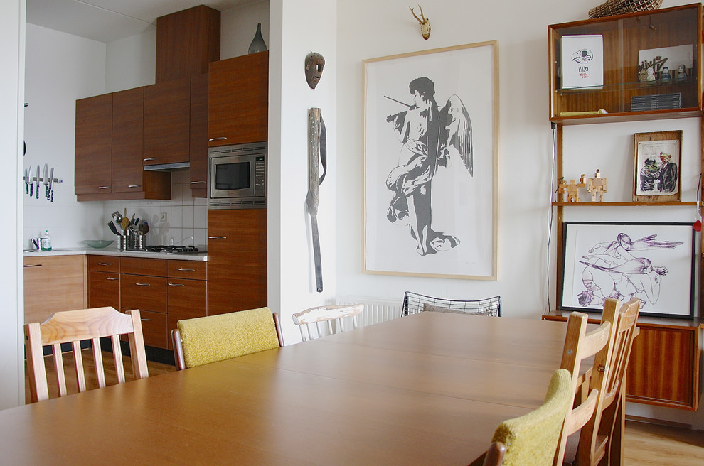 Immagine di una sala da pranzo aperta verso la cucina eclettica con pareti bianche