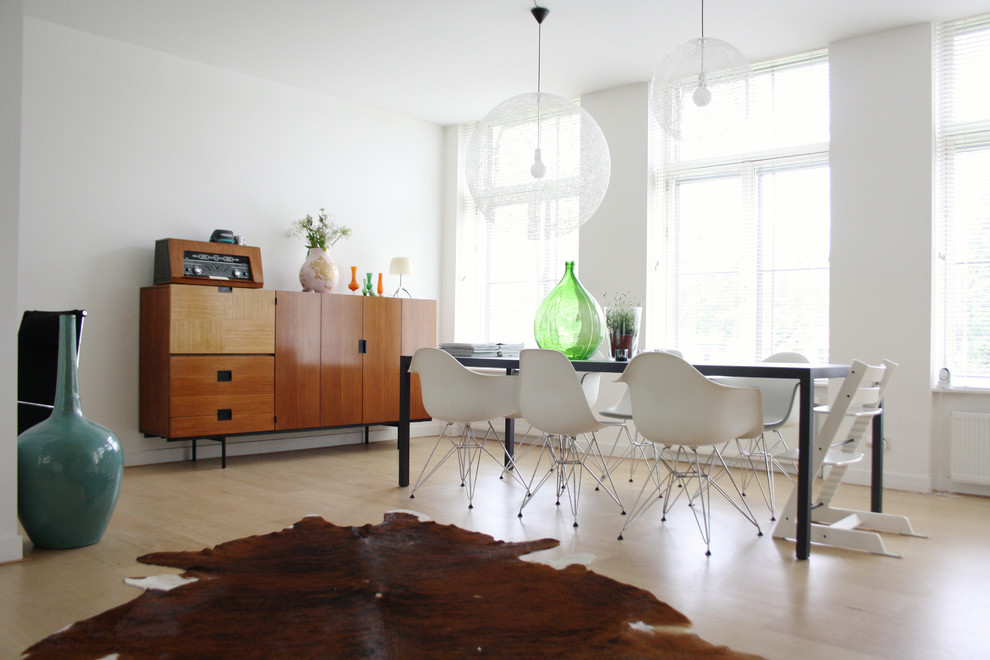 Midcentury dining room in Amsterdam with white walls, light hardwood flooring and feature lighting.