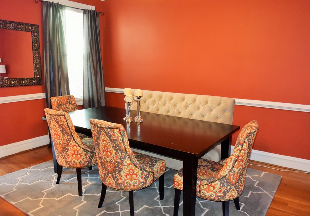 Idee per una sala da pranzo aperta verso la cucina minimalista con pareti arancioni e pavimento in legno massello medio