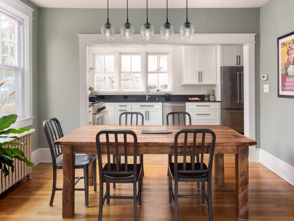 Cette photo montre une grande salle à manger ouverte sur la cuisine chic avec un mur vert, un sol en bois brun et un sol marron.