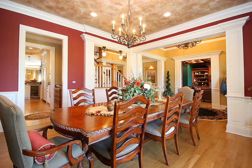 Immagine di una grande sala da pranzo tradizionale chiusa con pareti rosse, parquet chiaro e nessun camino