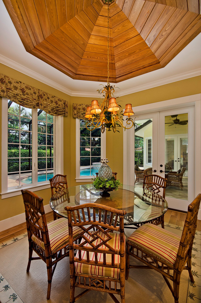 Foto di una piccola sala da pranzo tropicale chiusa con pareti gialle e pavimento in legno massello medio