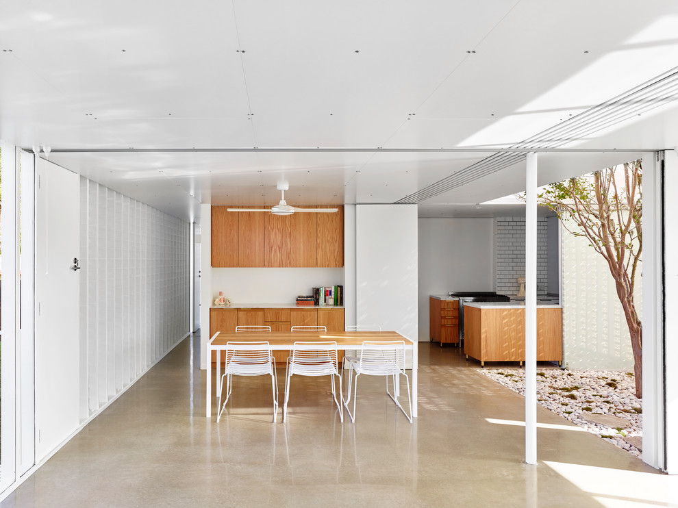 На фото: столовая среднего размера в современном стиле с белыми стенами и бетонным полом