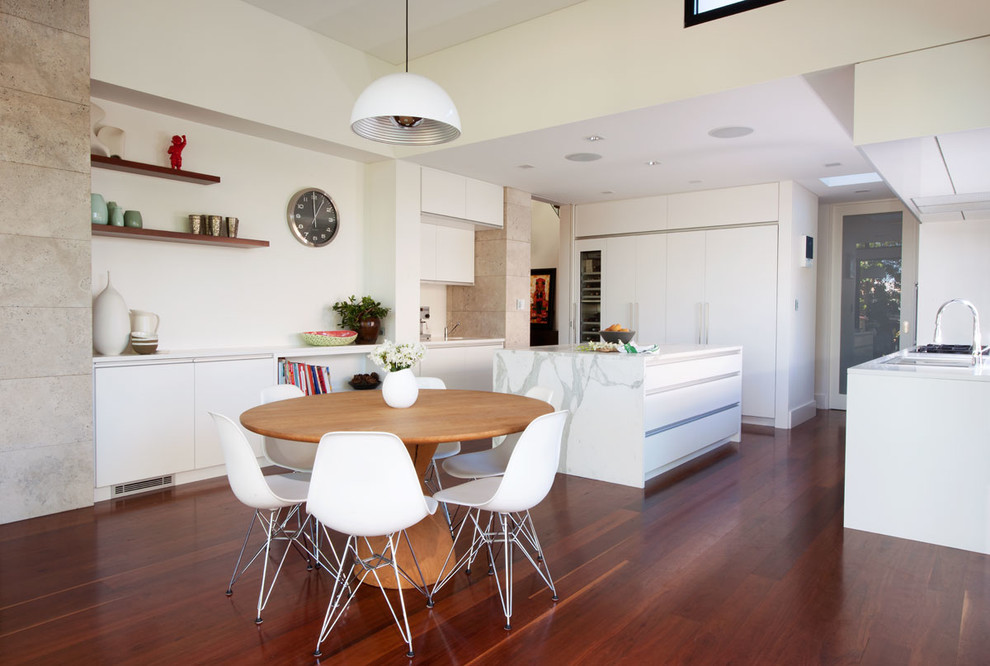 Стильный дизайн: кухня-столовая в современном стиле с белыми стенами и темным паркетным полом - последний тренд