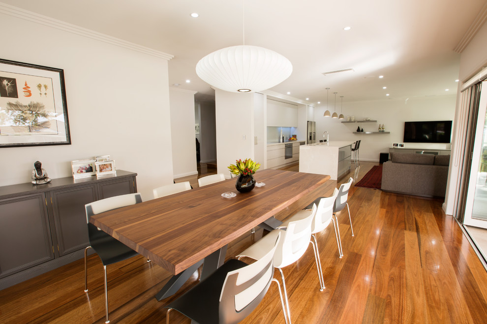 Aménagement d'une salle à manger ouverte sur la cuisine contemporaine avec un mur gris et un sol en bois brun.