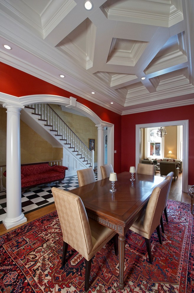Cette photo montre une salle à manger chic fermée et de taille moyenne avec un mur rouge, un sol en bois brun et aucune cheminée.