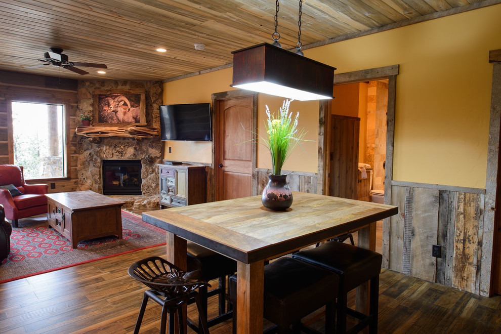 Foto på ett kök med matplats, med gula väggar, mörkt trägolv, en öppen hörnspis och en spiselkrans i sten
