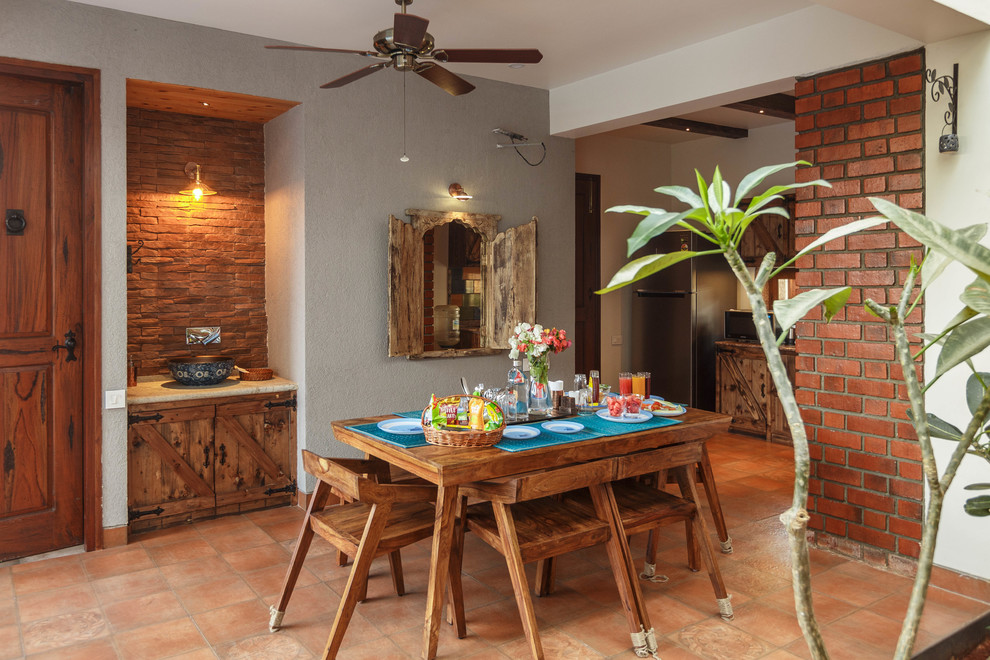 This is an example of a world-inspired dining room in Bengaluru with multi-coloured walls, brick flooring and brown floors.