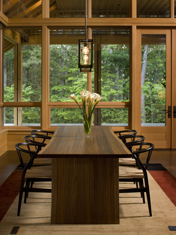 Cette image montre une salle à manger ouverte sur le salon design avec parquet foncé, un mur beige et un sol marron.