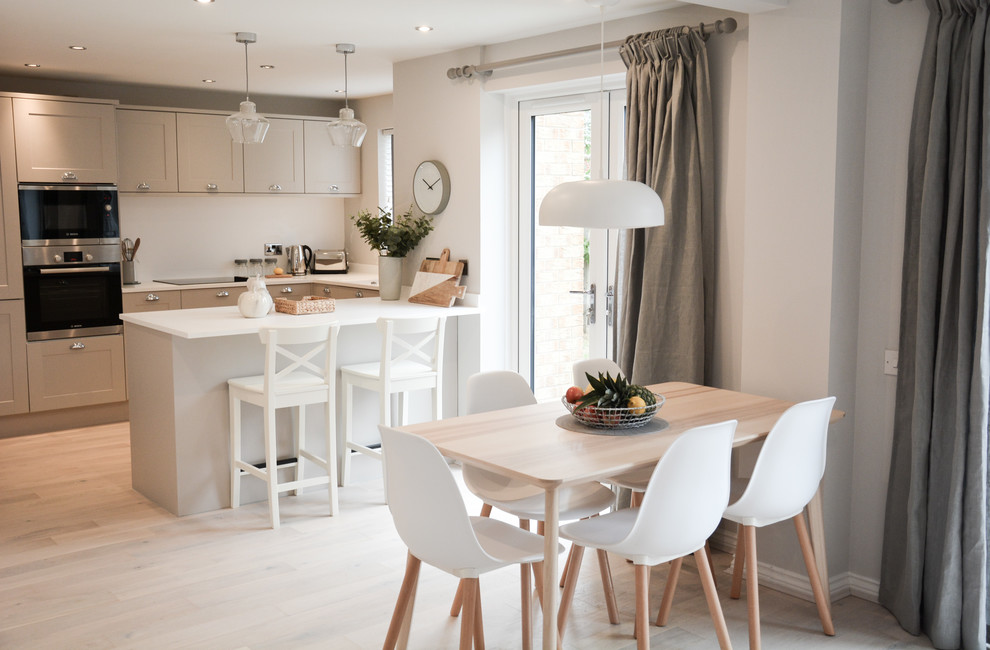 This is an example of a scandinavian dining room in Hampshire with white walls, light hardwood flooring and beige floors.