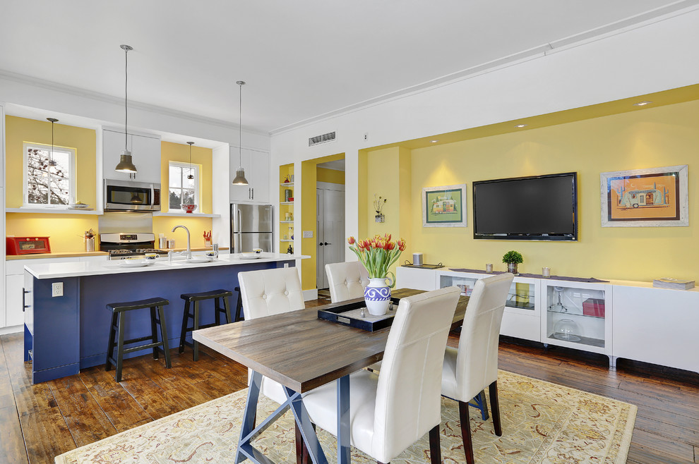 На фото: гостиная-столовая среднего размера в современном стиле с желтыми стенами, темным паркетным полом и коричневым полом с