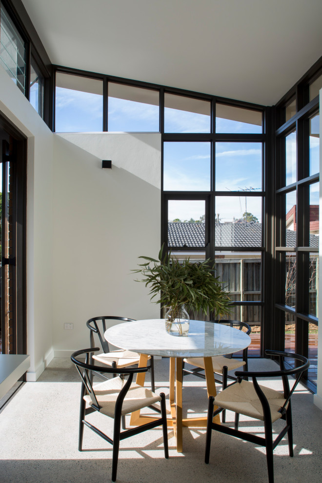 Immagine di una piccola sala da pranzo aperta verso il soggiorno minimal con pareti bianche, pavimento in cemento e pavimento grigio