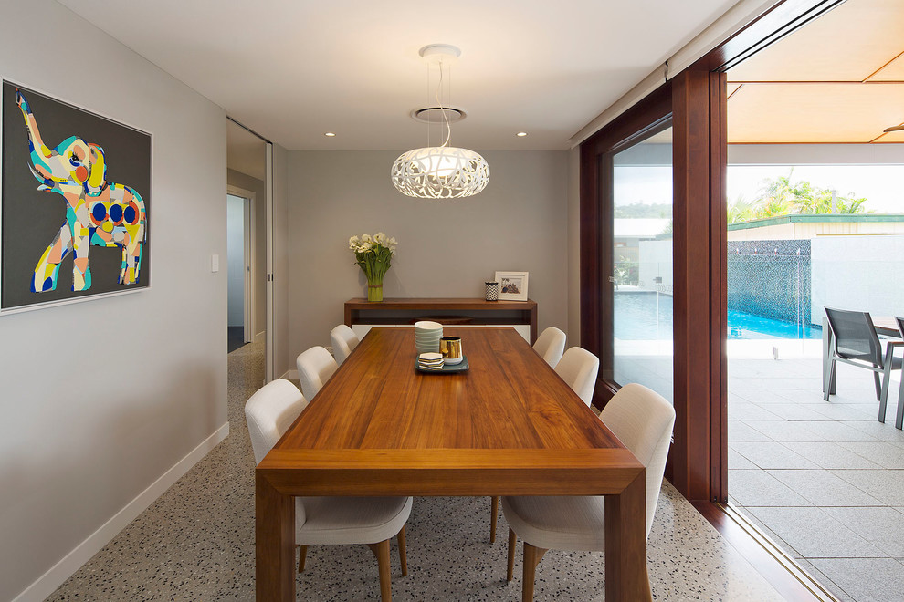 Cette image montre une petite salle à manger ouverte sur le salon design avec un mur gris, sol en béton ciré, aucune cheminée et un sol gris.