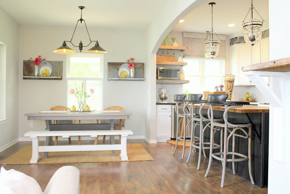 Immagine di una sala da pranzo aperta verso la cucina country con pareti grigie, parquet chiaro e nessun camino