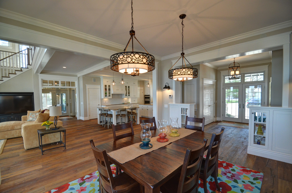 Inspiration pour une grande salle à manger ouverte sur le salon craftsman avec un mur beige, un sol en bois brun et éclairage.