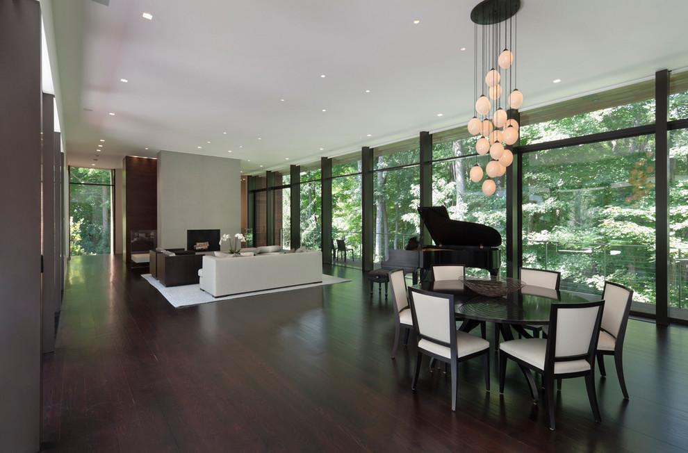 Large modern open plan dining room in New York with white walls, dark hardwood flooring and a two-sided fireplace.