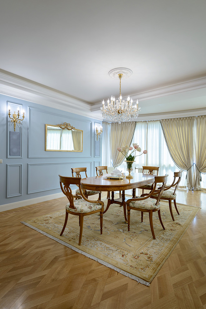 На фото: большая отдельная столовая в классическом стиле с синими стенами, светлым паркетным полом и стандартным камином