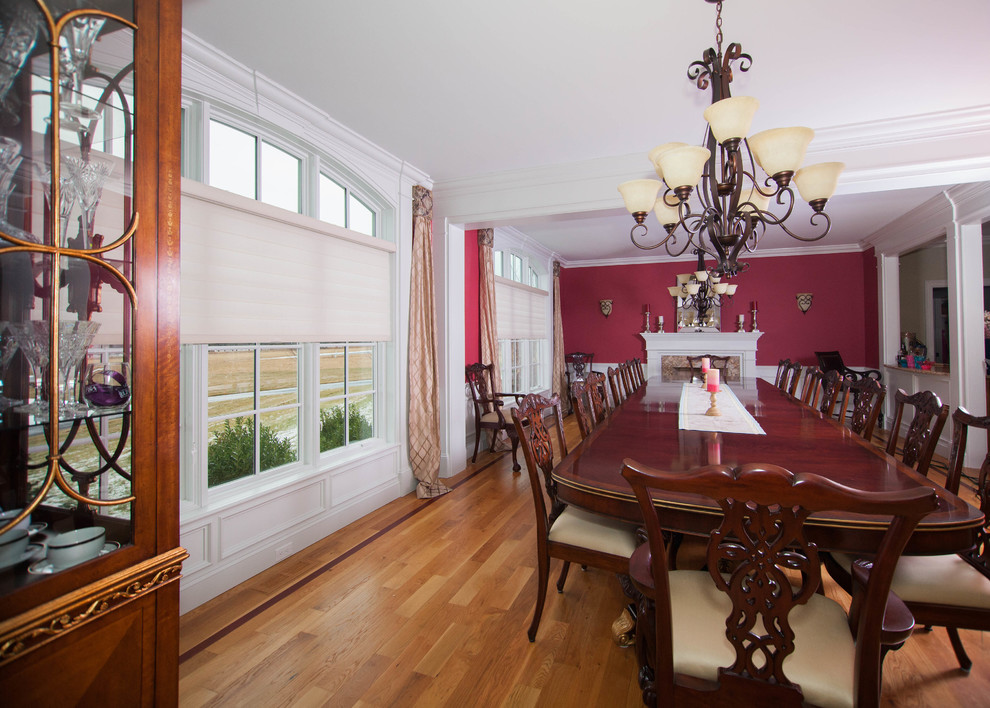 Geschlossenes, Geräumiges Klassisches Esszimmer mit roter Wandfarbe, braunem Holzboden, Kamin, Kaminumrandung aus Holz und braunem Boden in Boston