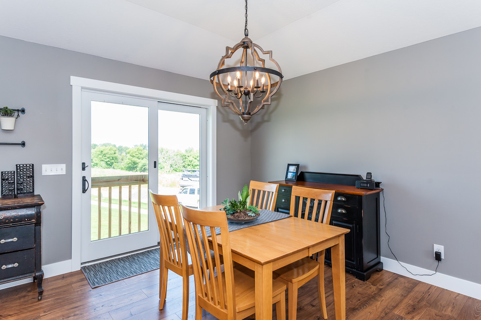 Idée de décoration pour une petite salle à manger ouverte sur le salon champêtre avec un mur gris, parquet foncé et un sol marron.