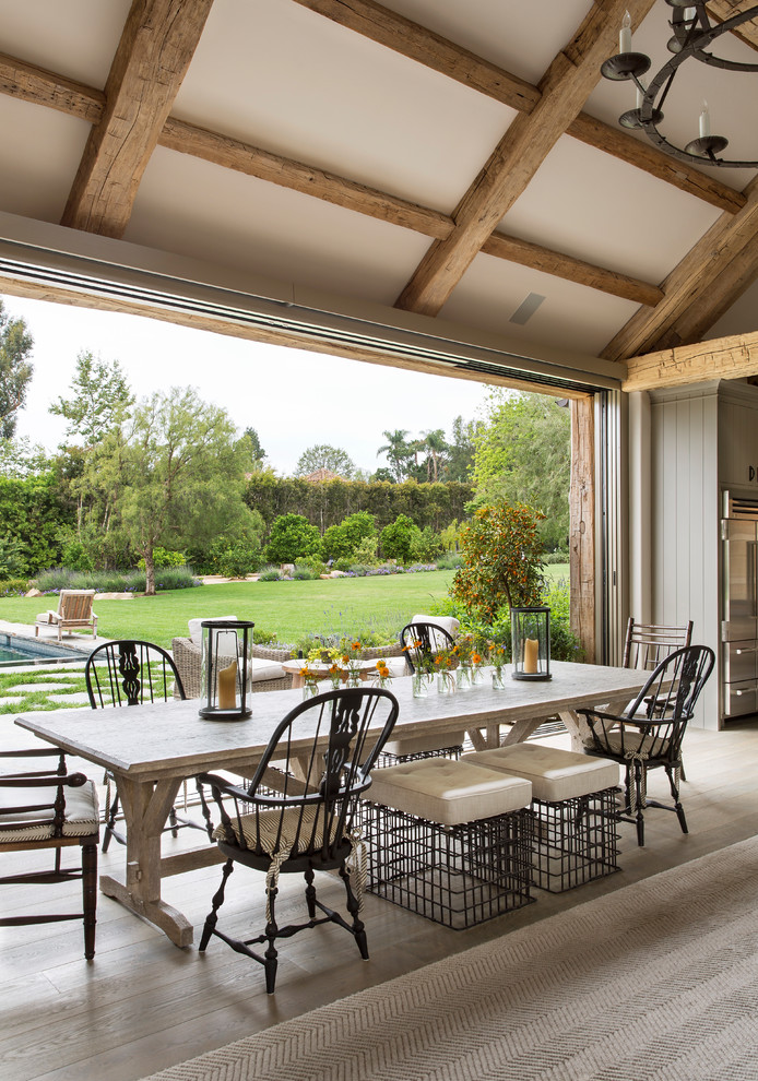Immagine di una sala da pranzo aperta verso il soggiorno country con pareti beige e parquet chiaro